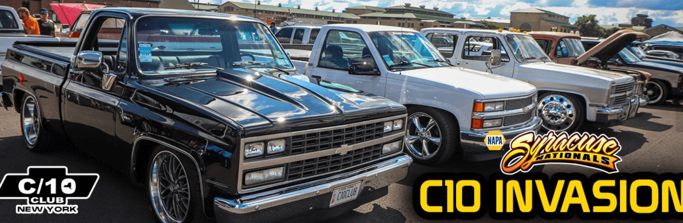 A row of classic Chevrolet C10 pickup trucks are parked at the C10 Invasion event during Syracuse Nationals, with Blues Festival vibes, event logos, and a C10 Club New York banner in the foreground.